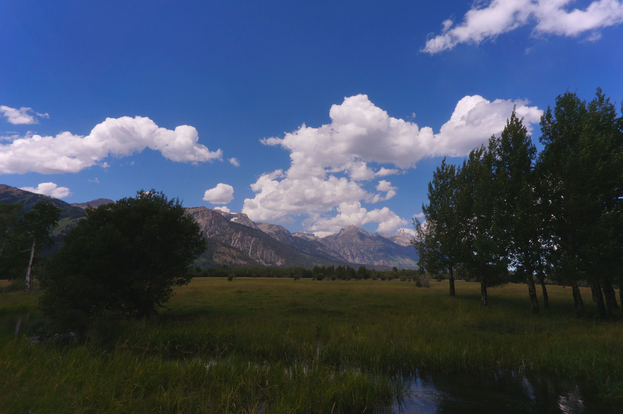 A mountain peak below a blue sky with scattered clouds.