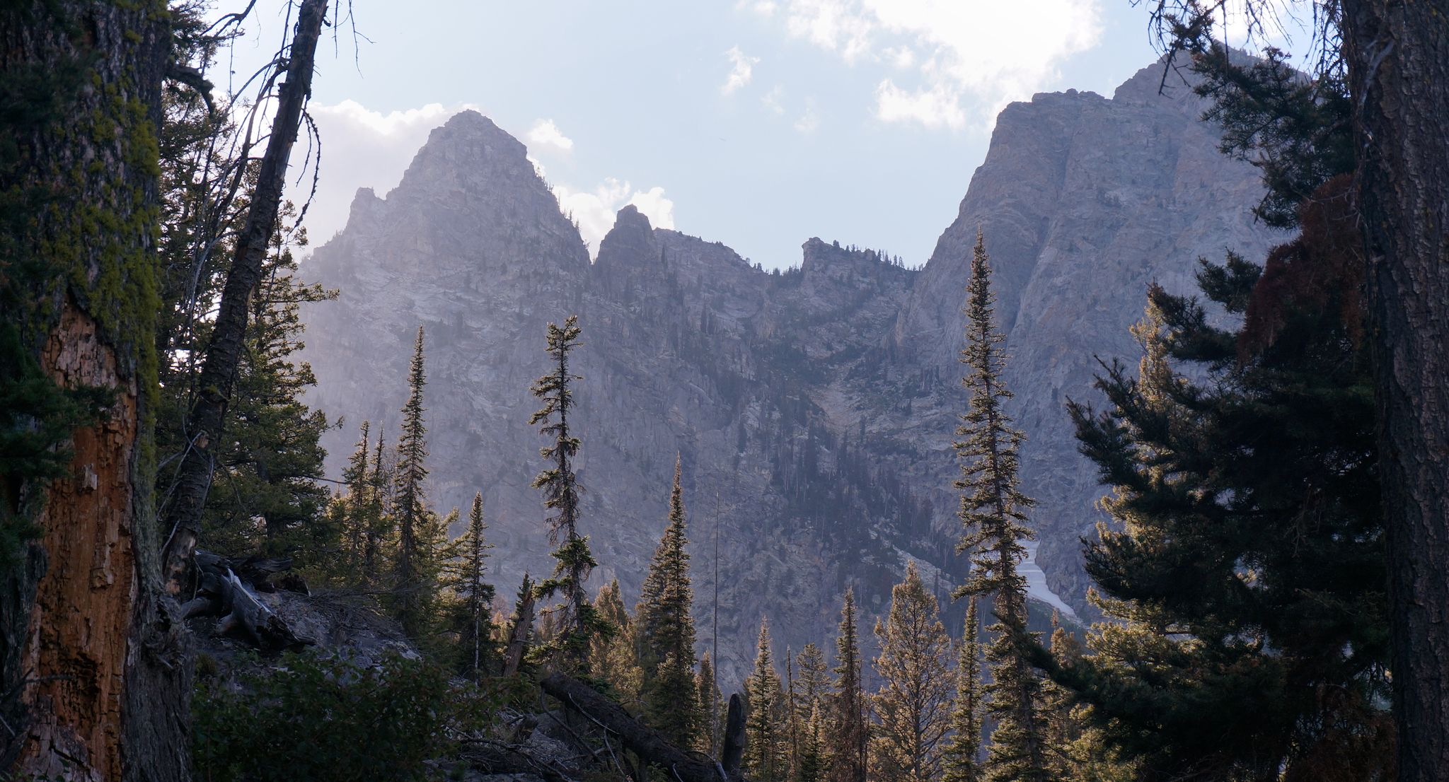 A mountain peak below a blue sky with scattered clouds.