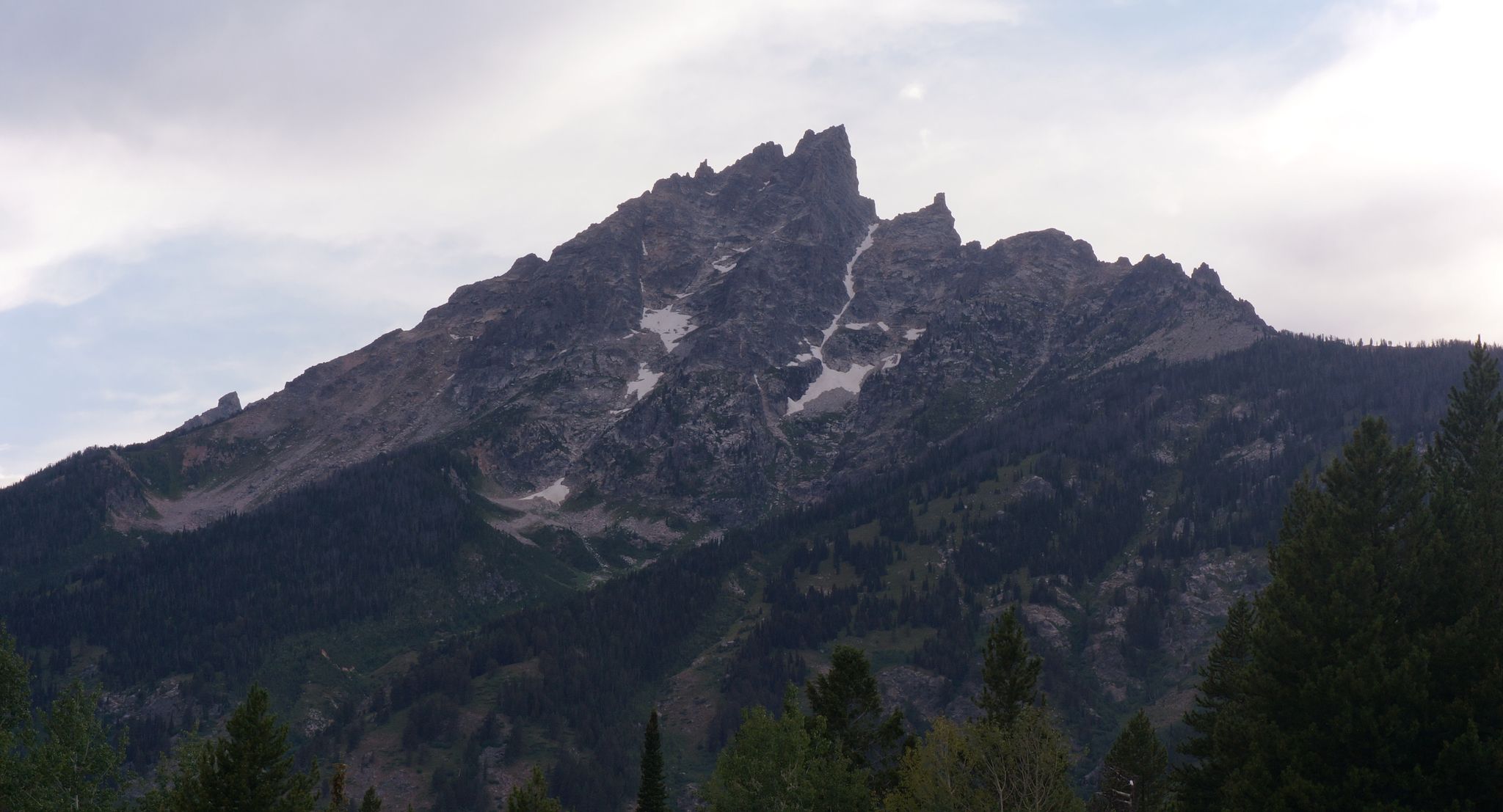 A mountain peak below a blue sky with scattered clouds.
