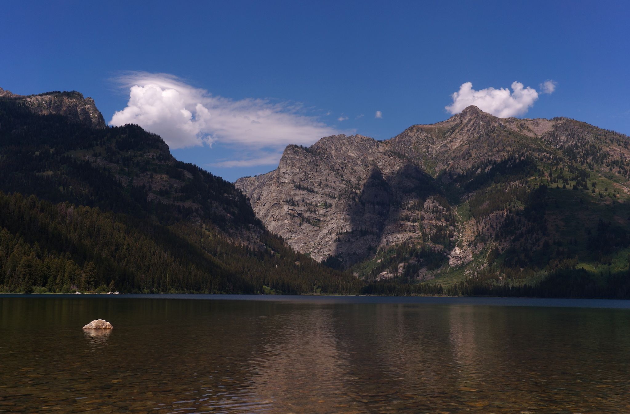 A mountain peak below a blue sky with scattered clouds.